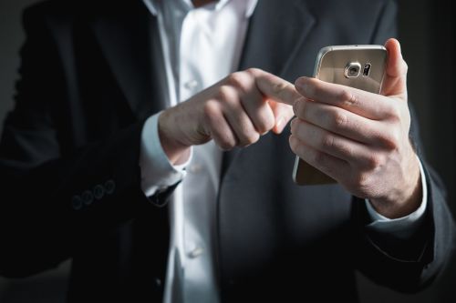 Man in suit holding mobile phone | website design company | VIEWS Digital Marketing