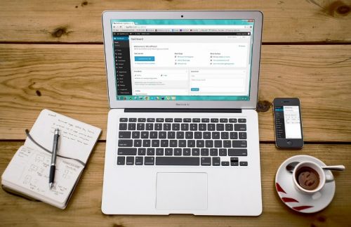 Laptop on table next to notebook and phone, with WordPress website open | website design company | VIEWS Digital Marketing