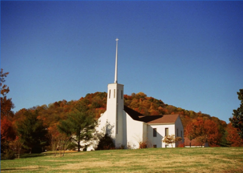 White church building set on grassy hilltop with trees behind | VIEWS Digital Marketing