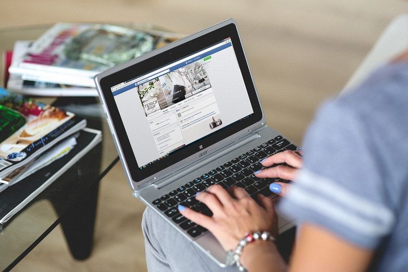 Woman sitting with laptop with Facebook open | Social Media Paid Advertising | VIEWS Digital Marketing